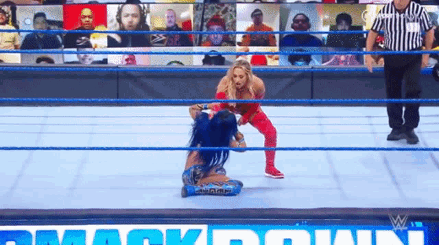 two women are wrestling in a wrestling ring with a referee .