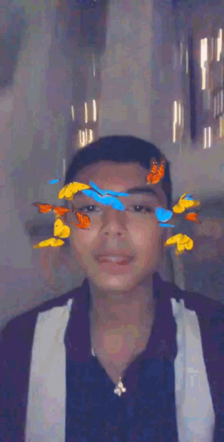 a young man with butterflies on his face looks at the camera