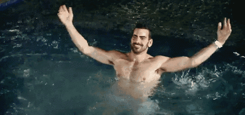 a shirtless man is swimming in a pool with his arms outstretched and giving the middle finger .