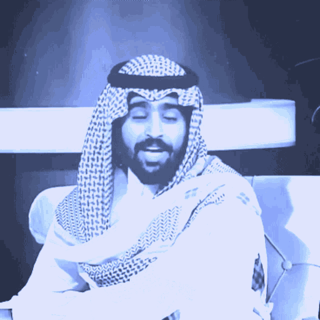 a man with a beard is wearing a head scarf and a white shirt