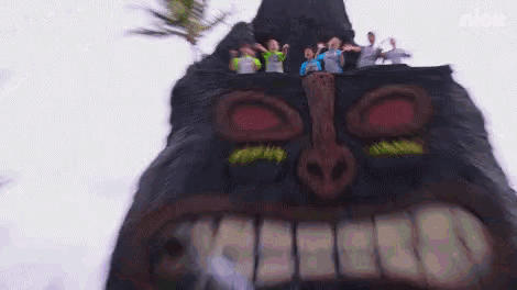 a group of people standing on top of a giant tiki statue .