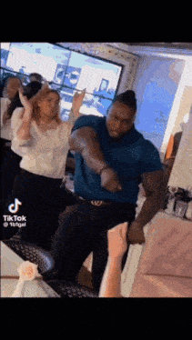 a man in a blue shirt is dancing with a woman in a restaurant .