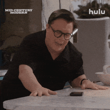 a man sitting at a table with hulu written on the bottom of the screen