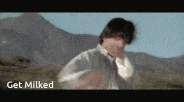 a man covering his face in a field with the words get milked above him