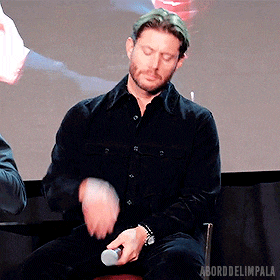a man in a black shirt is sitting on a stool holding a microphone ..