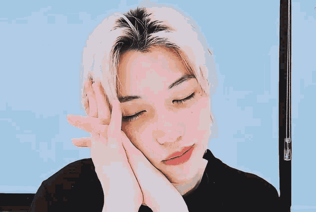 a close up of a person 's face with their eyes closed and their hands on their face
