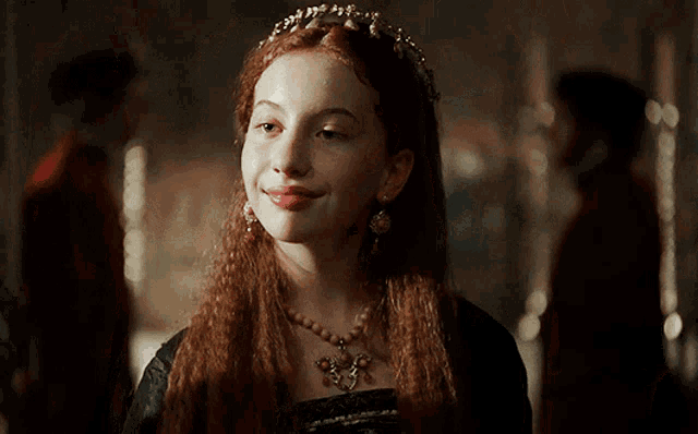a woman with red hair is wearing a tiara and necklace