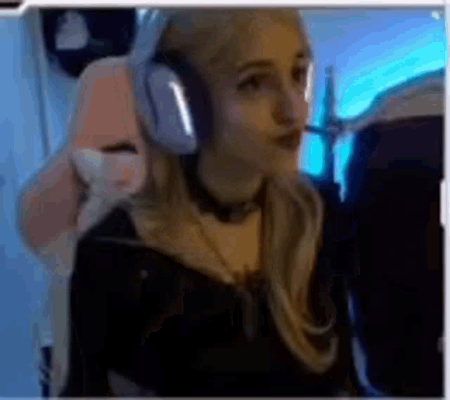 a woman wearing headphones and a choker is sitting in a gaming chair .