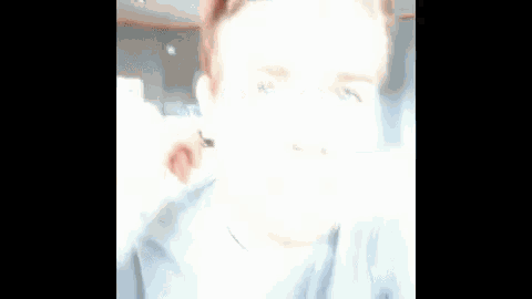 a man in a grey shirt is making a funny face while looking at the camera .