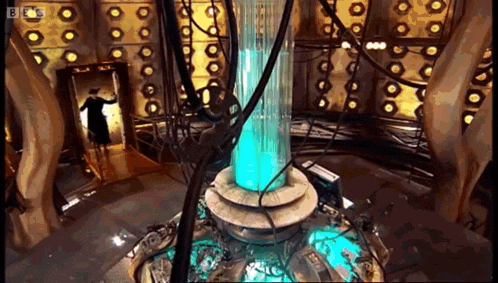 a woman in a black dress is standing in a room with a large blue object in the middle of it .