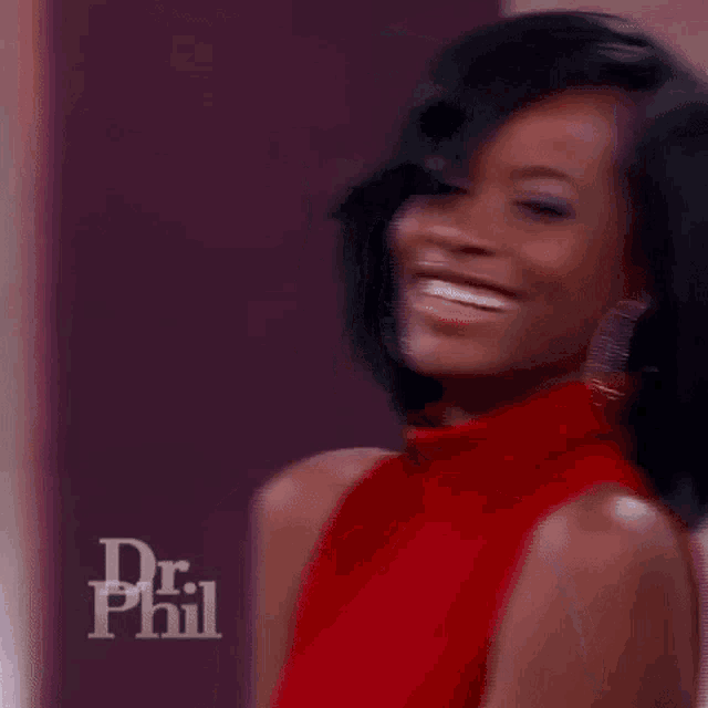 a woman in a red dress and hoop earrings is smiling and looking at the camera .