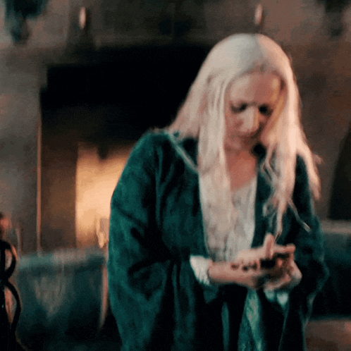 a woman with long white hair is looking at her phone