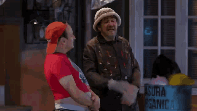 a man in a hat is standing next to a woman in a red crop top