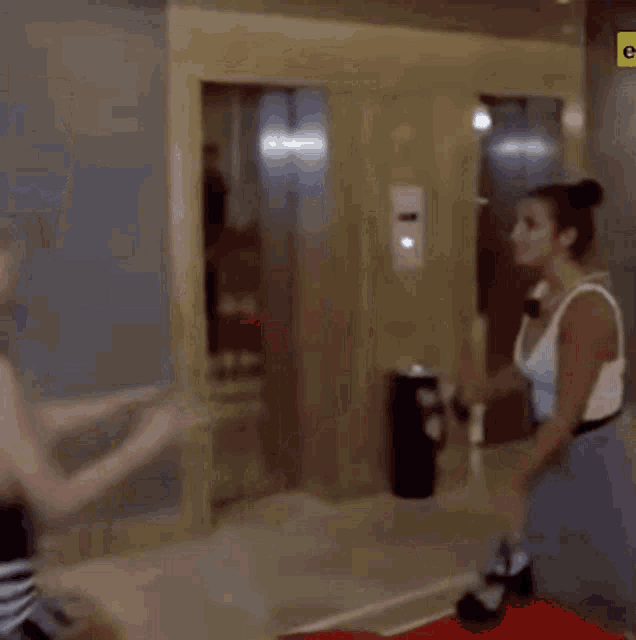 a man and a woman are fighting in a room in front of an elevator .