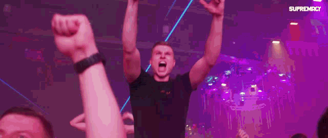 a man is raising his fist in the air in front of a sign that says " supremex "