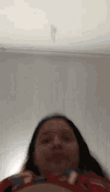 a woman is holding a remote control in her hand and making a face .