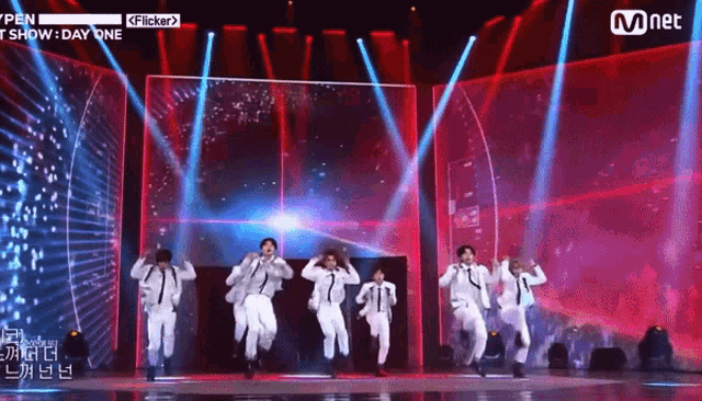 a group of men are dancing on a stage with a sign that says mnet on it