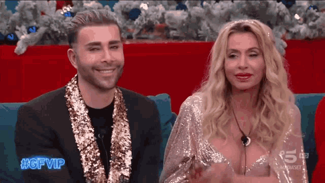 a man and a woman are sitting next to each other on a couch with the hashtag #gfvip on the screen