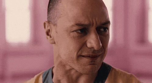a man with a shaved head is making a funny face in a pink room .