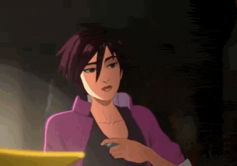 a woman in a purple jacket is sitting in a dark room looking at her phone .