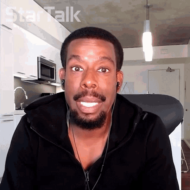 a man wearing ear buds looks at the camera with the word star talk behind him