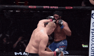 two men are fighting in a boxing ring with a sign that says crypto.com