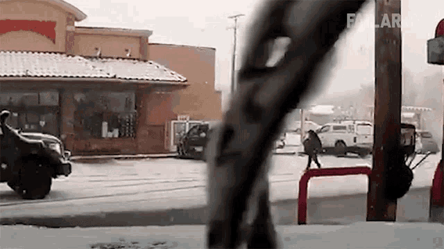 a truck is driving down a snow covered street in front of a restaurant .