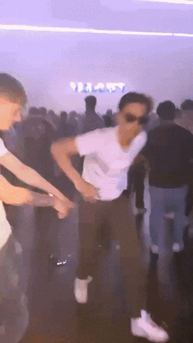a group of people are dancing in a room with a sign that says happy