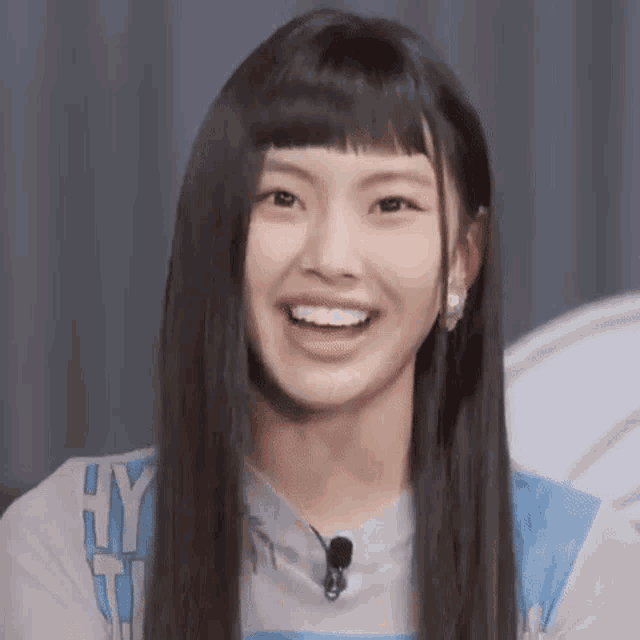 a young woman with long black hair is smiling and wearing a blue shirt .