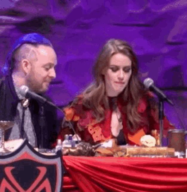 a man and woman are sitting at a table with microphones .