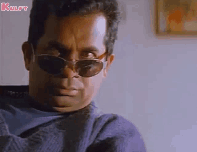 a man wearing sunglasses and a sweater is making a face .