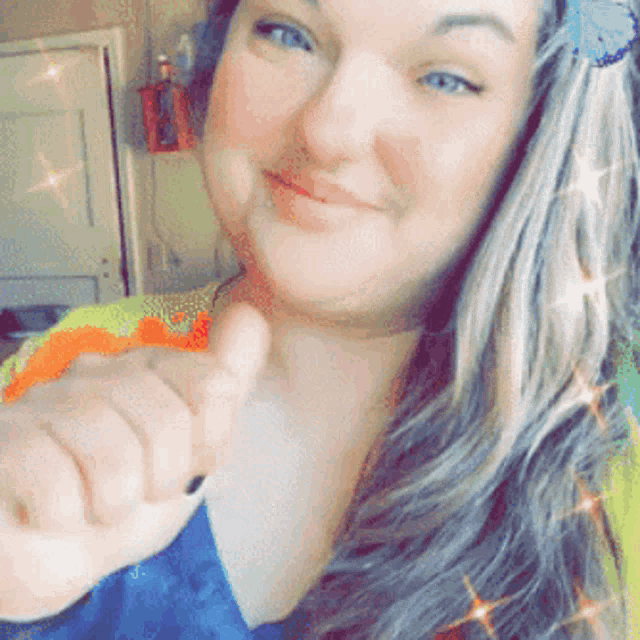 a woman is giving a thumbs up and has a flower in her hair