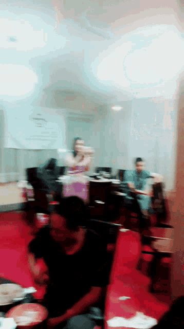 a blurry picture of people sitting in a room with a sign that says ' a ' on it