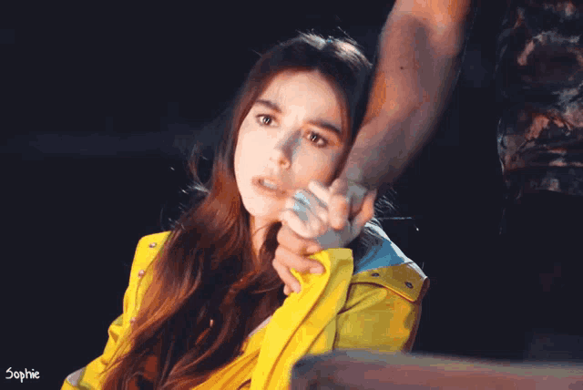a woman in a yellow jacket is being held by a man with sophie written on the bottom