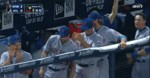 a group of baseball players standing in a dugout with a banner that says " academy " on it