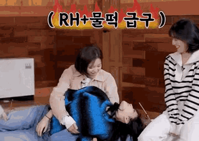two women are sitting next to each other on a bed and one is laying on her back .