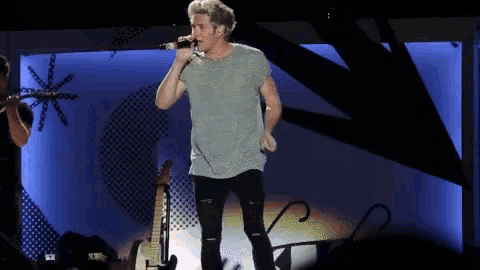 a man singing into a microphone on a stage