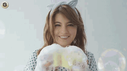 a woman in a polka dot dress is holding soap bubbles in front of her face .