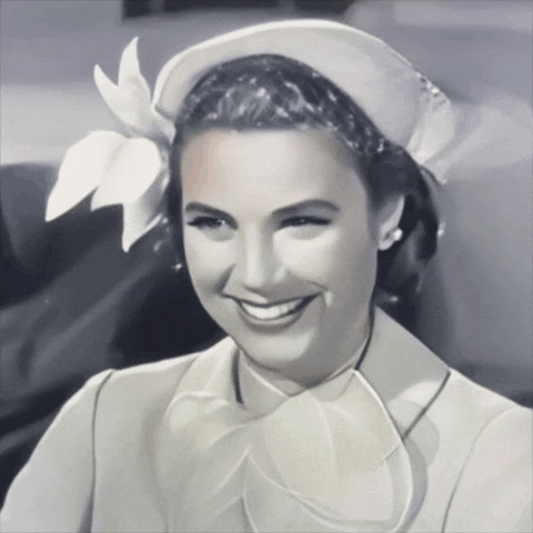 a black and white photo of a woman wearing a hat and smiling