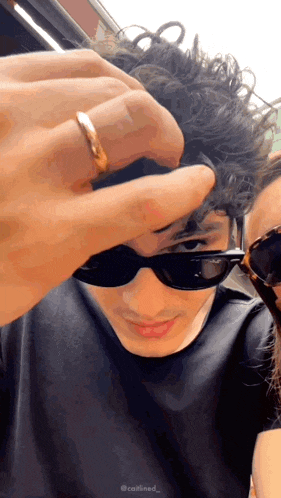 a man wearing sunglasses and a gold ring is being held by a woman