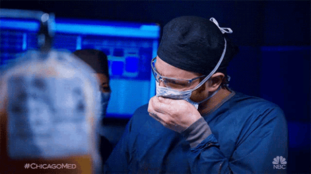 a surgeon wearing a mask and goggles is coughing while wearing a chicagomed shirt