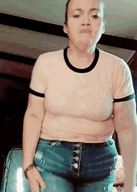 a woman wearing a t-shirt and jeans is standing in a room
