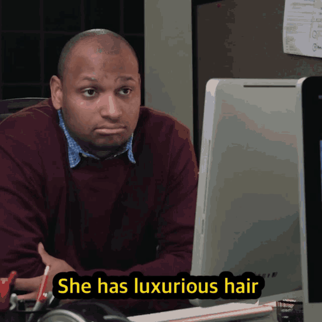 a man sits at a desk with a computer and says she has luxurious hair
