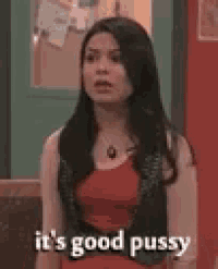 a woman in a red dress is standing in front of a door and saying it 's good pussy .