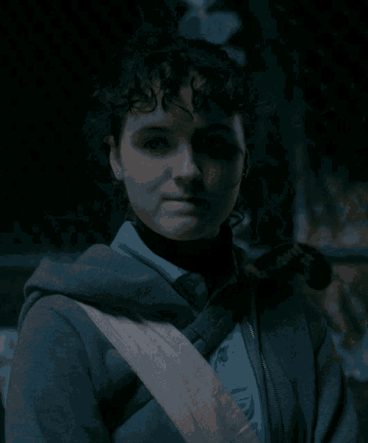 a girl with curly hair wearing a grey hoodie