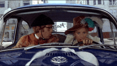 a man and a woman in a blue vw car