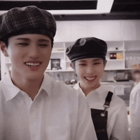 two young men wearing hats and aprons are smiling in a kitchen