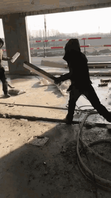 a man in a hooded jacket is holding a large saw