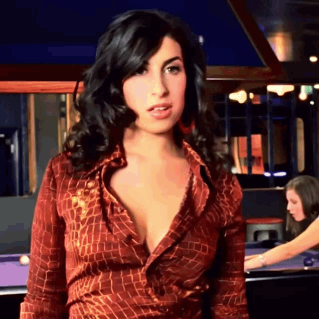 a woman in a very plunging neckline shirt stands in front of a pool table