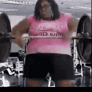 a woman is doing squats with a barbell in a gym .